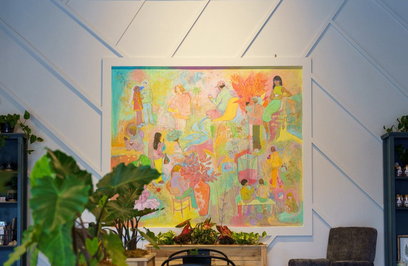 Colorful abstract painting on a wall with plants and furniture in a room.